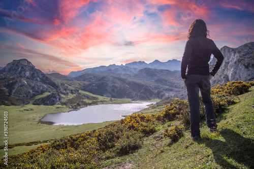 A young woman looking at the beautiful Covadonga lake in Asturias in a beautiful spring sunset, Picos de Europa. Spain photo