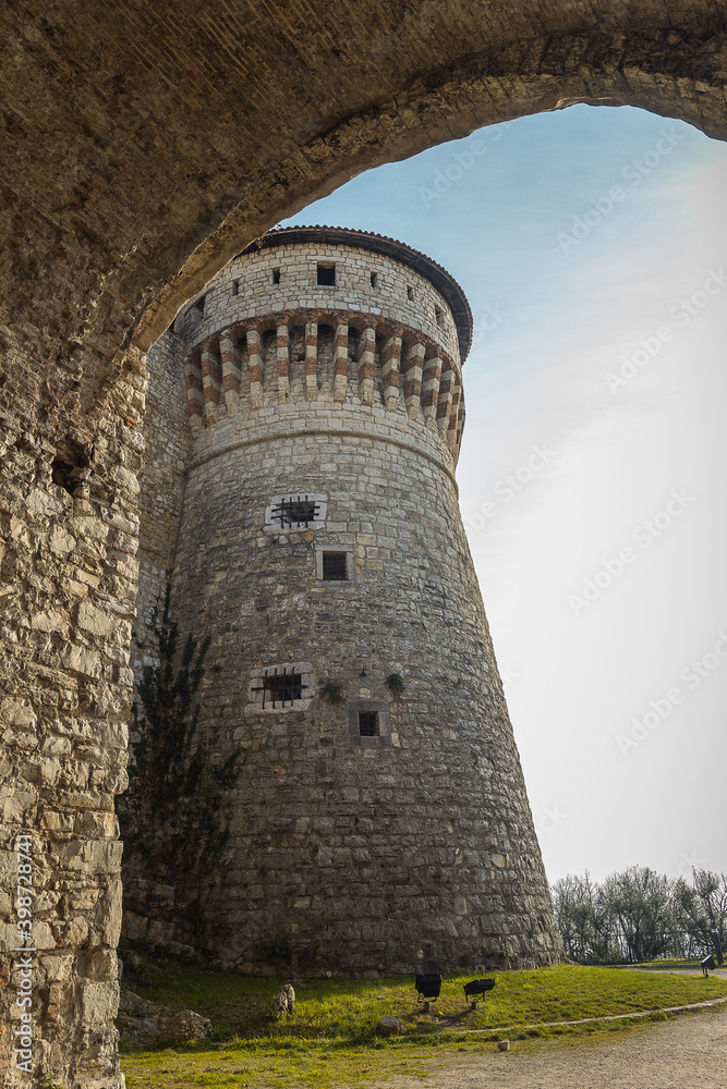 Big tower in the Medieval castle of the city of Brescia on a sunny clear day against a bright blue sky. Part of Brescia castle on the hill Cidneo. Castello di Brescia, Lombardy, Italy.