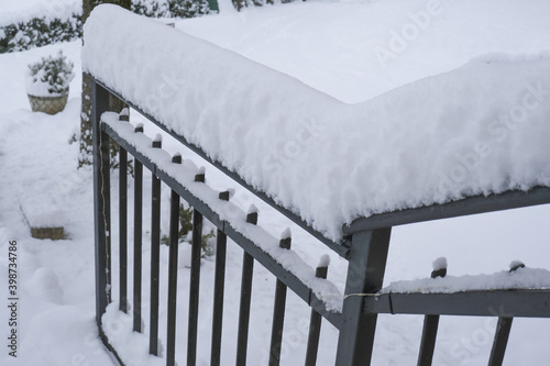 snow covered black metal handrail by the house across snowy backyard. Winter season