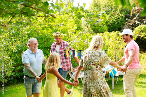 Family dancing in garden around maypole