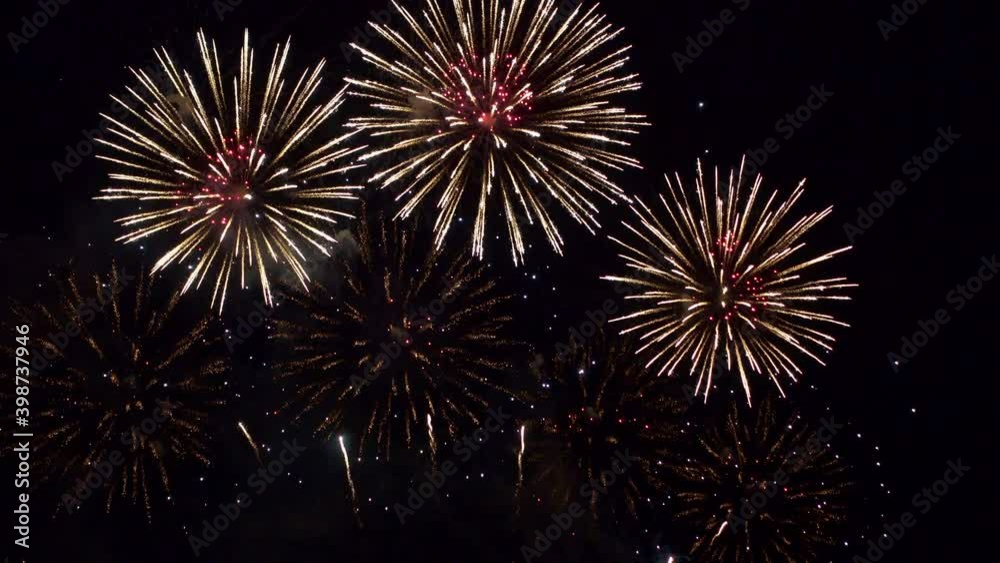 Stunning fireworks show fills the dark night sky with color as dozens of explosions spread across the screen. Shining sparkling pyrotechnic display celebrating an event.