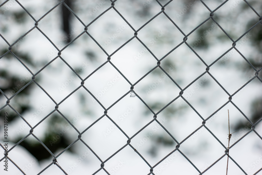 Wire mesh fence texture front view shallow depth of field snowy landscape background Wire mesh fence texture front view shallow depth of field snowy landscape background