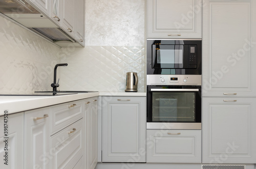 Beautiful classic kitchen in light gray, white tones in a new house.