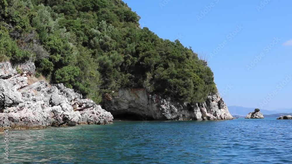View from boat on rocky wooded cliffs coast and wild cave, nature of Lefkada island in Greece. Summer vacation travel to Ionian Sea View from boat on rocky wooded cliffs coast and wild cave, nature of Lefkada island in Greece. Summer vacation travel to Ionian Sea