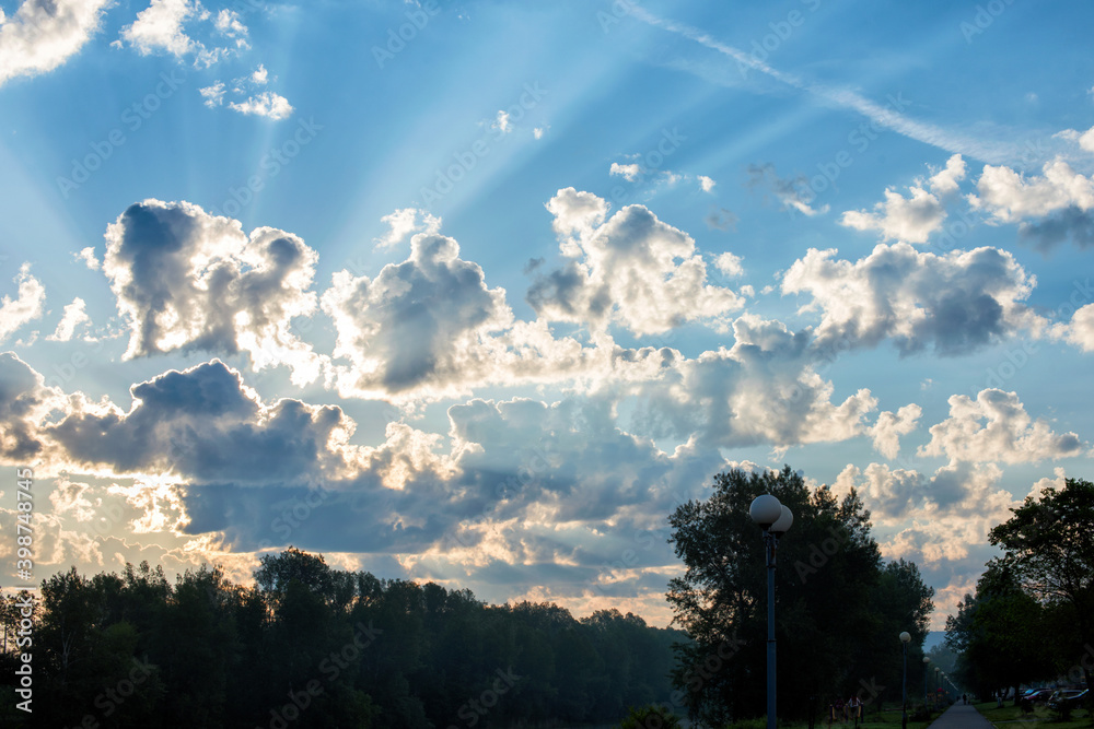 Bright sunset on the background of cloudy sky and forest.