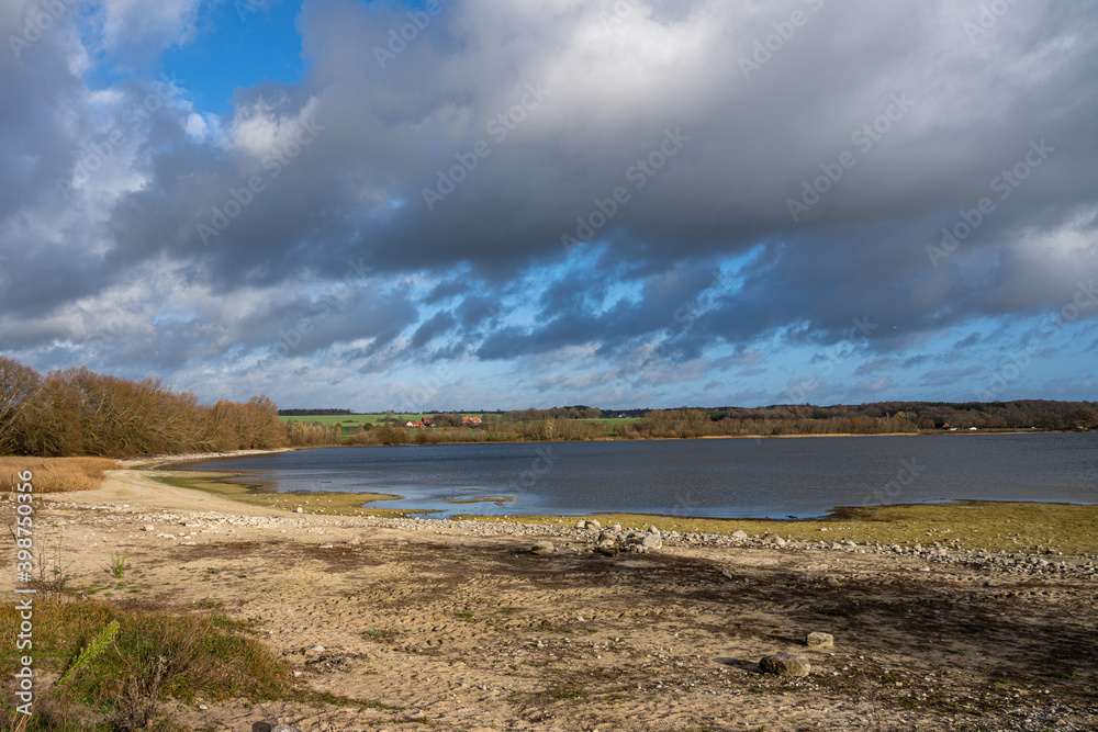 A shoreline at a lake with a dramatic sky in the background. Picture from Lake Vomb, Scania county, Sweden A shoreline at a lake with a dramatic sky in the background. Picture from Lake Vomb, Scania county, Sweden