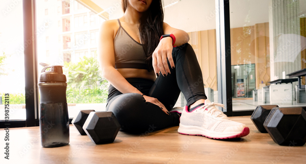 Woman exercise workout in gym fitness breaking relax after training sport with dumbbell and water bottle. Woman exercise workout in gym fitness breaking relax after training sport with dumbbell and water bottle.
