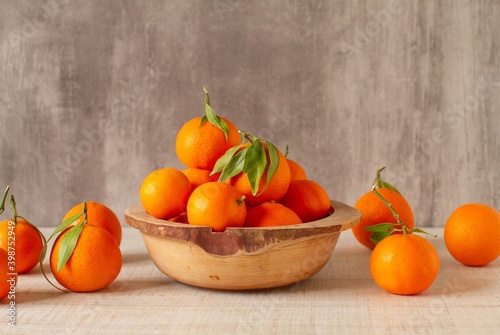 Fresh mandarin oranges fruit or tangerines with leaves on wooden table on a gray background