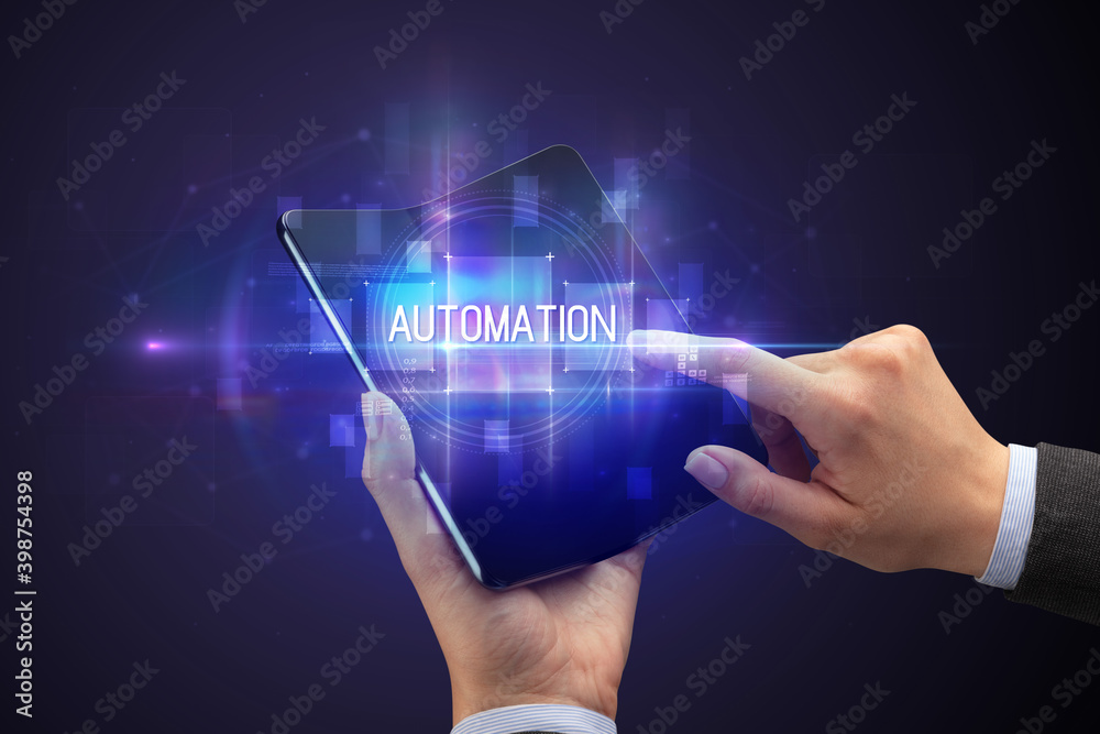 Businessman holding a foldable smartphone with AUTOMATION inscription, new technology concept Businessman holding a foldable smartphone with AUTOMATION inscription, new technology concept