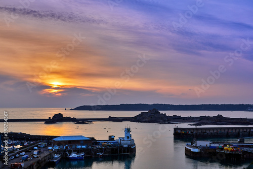 Image of St Helier Harbour Pierheads at sunset with Elizabeth Castle and St Aubins Bay. Jersey CI