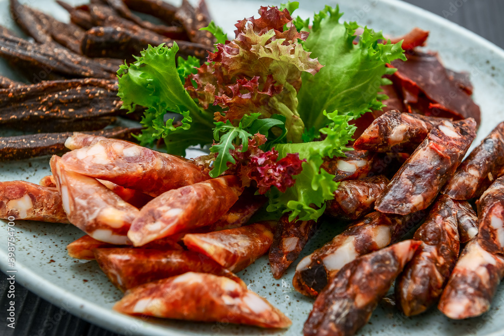 Traditional dry-cured sausage and jerky on a plate Traditional dry-cured sausage and jerky on a plate