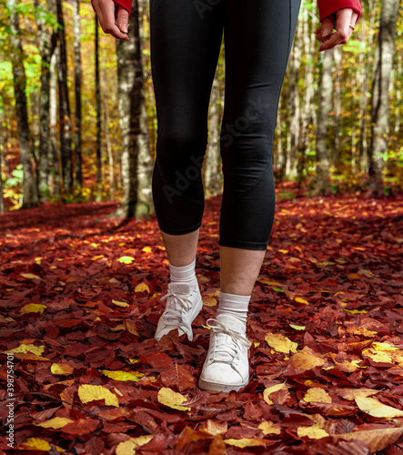 The woman doing sports in the forest in autumn ties the laces of her sneakers.