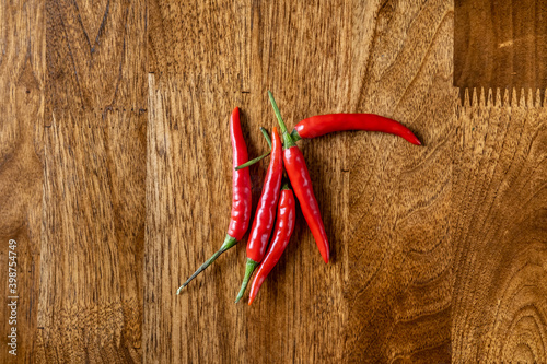 Background with red spicy chilly on the wooden table with copy space. Food concept for restaurant, cafe, delivery, spring, vegan, eco, raw.