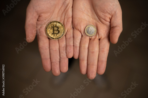 Caucasian hands shows one Bitcoin coin and one Euro Coin. New finance concept. Comparison between currencies, fiat and crypto. Two hands