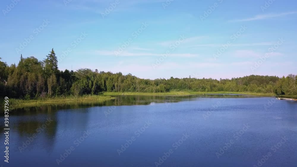 Drone shot over a beautiful lake near a forest Drone shot over a beautiful lake near a forest