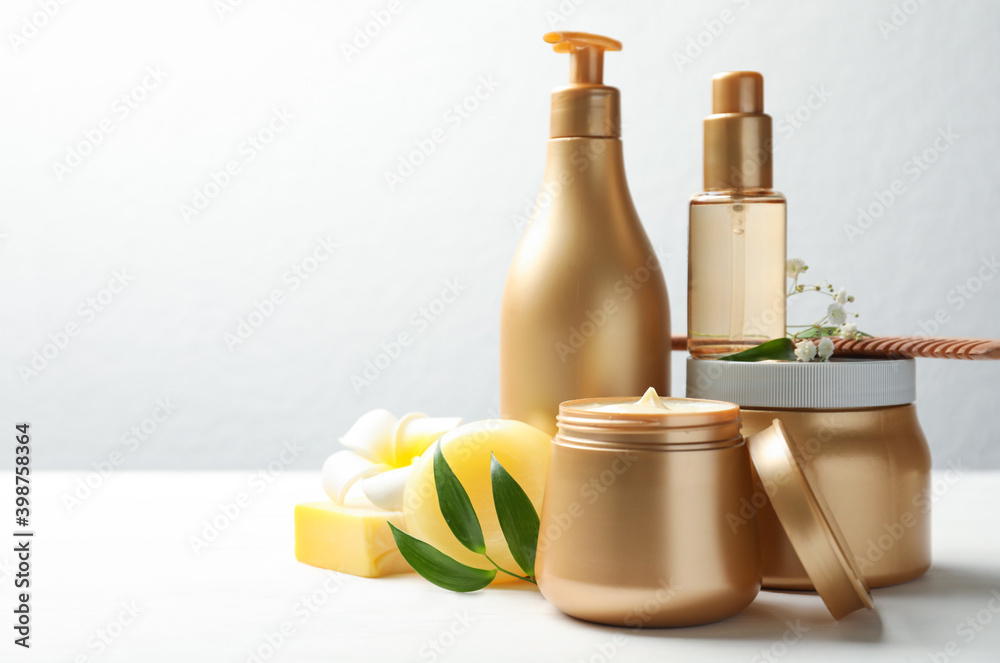Set of hair cosmetic products and flowers on white wooden table. Space for text Set of hair cosmetic products and flowers on white wooden table. Space for text