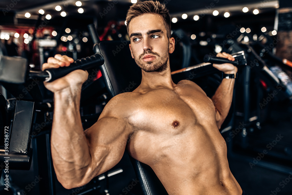 young muscular man, shirtless, working out in the gym, doing chest and arm exercises young muscular man, shirtless, working out in the gym, doing chest and arm exercises