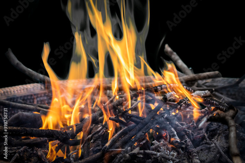 Sticks in a firepit with orange flame at night - Close-up