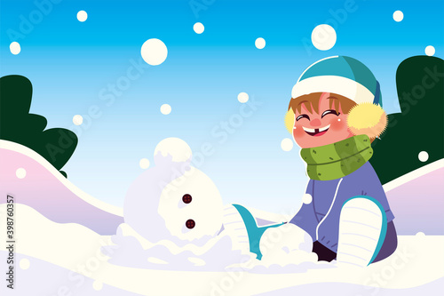 happy boy with warm clothes sitting in snow playing