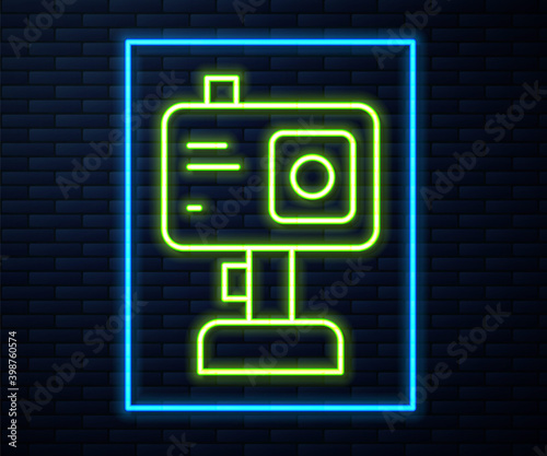 Glowing neon line Action extreme camera icon isolated on brick wall background. Video camera equipment for filming extreme sports.  Vector.