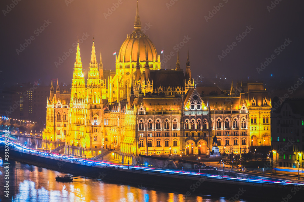 A side view of the Hungarian Parliament building along the Danube River at night with the building lit up 