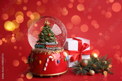 Beautiful snow globe and Christmas decor on red background. Bokeh effect