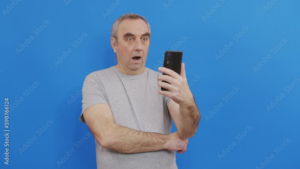 Happy senior elderly man holding smart phone watching mobile video calling online looking at screen. Happy senior elderly man holding smart phone watching mobile video calling online looking at screen.