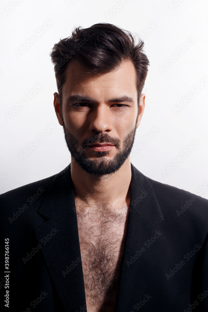 Closeup portrait of a handsome, brutal bearded man posing in black suit, with naked torso, isolated white background. Closeup portrait of a handsome, brutal bearded man posing in black suit, with naked torso, isolated white background.