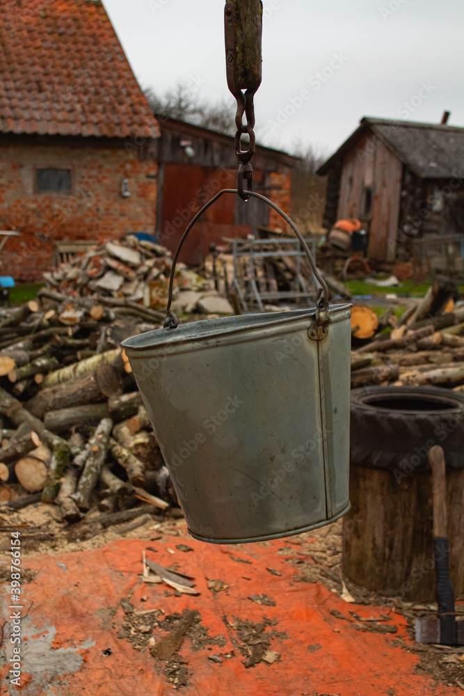 A bucket of well close-up against the background of firewood and buildings A bucket of well close-up against the background of firewood and buildings