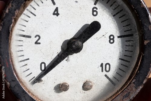 Close-up of an old industrial pressure gauge display with worn protective glass. Macro