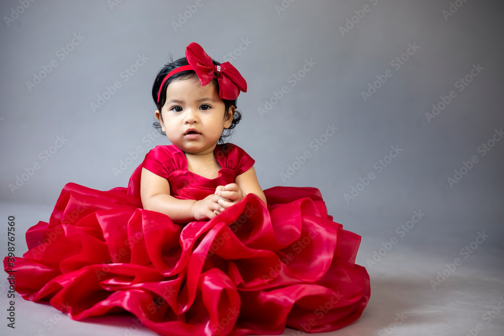 Lovely cute little Asian girl in a red dress is playing merrily and happily in her own home, promoting her skills and creativity..