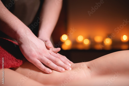 Sports massage of the thigh for a woman in a professional massage salon with contrasting light