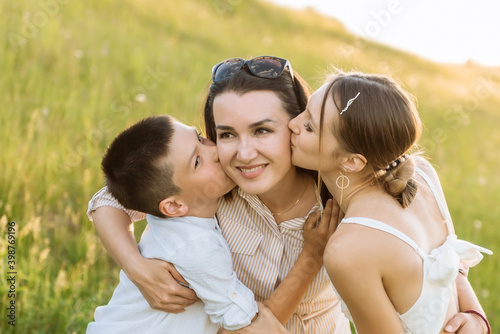 happy mother with children, daughter and son. children kiss their mother on the cheeks