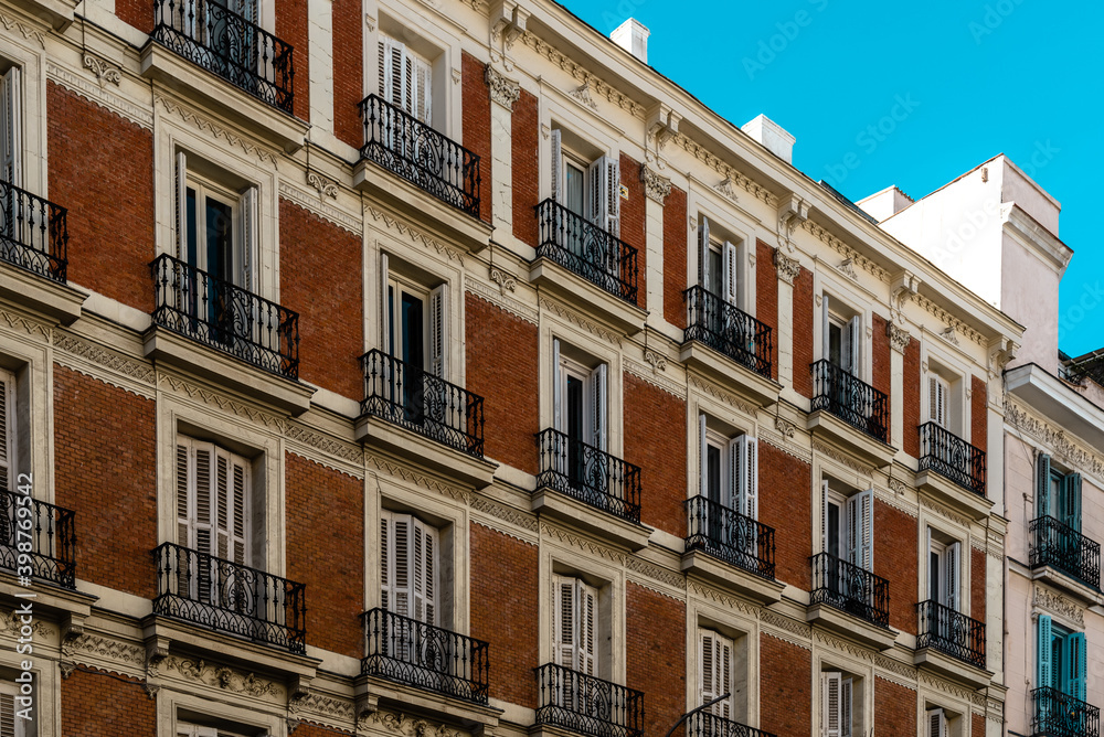 Old residential building with brick facade and iron balconies in Madrid