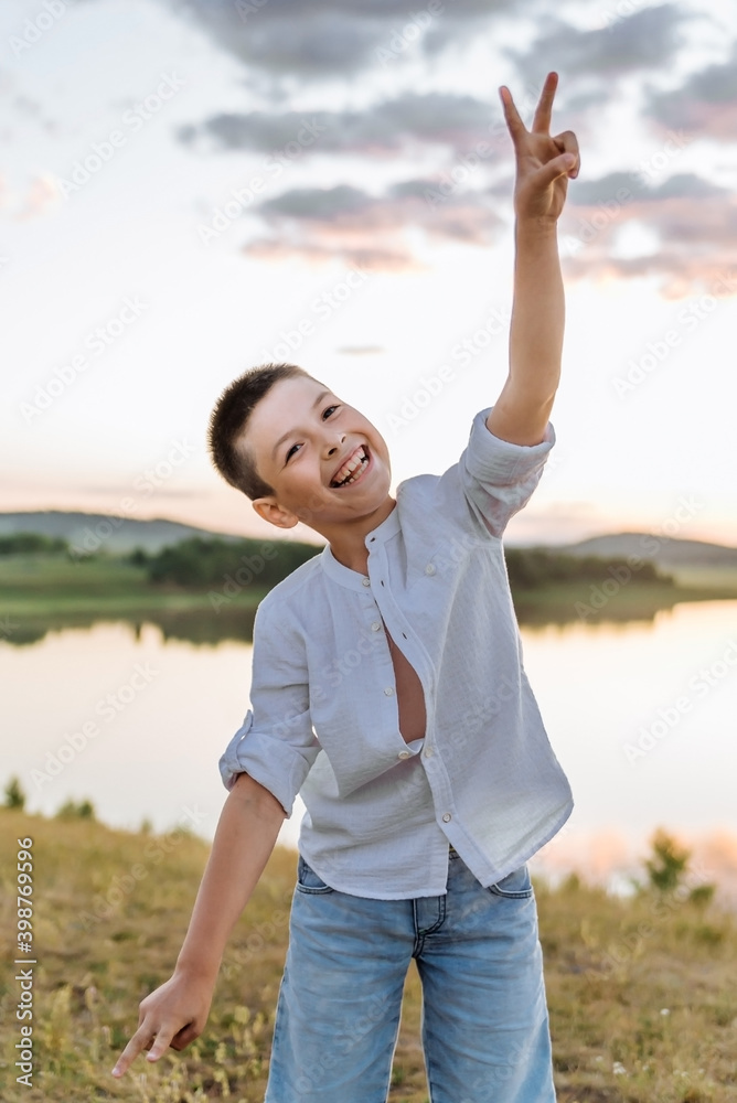 positive, happy boy rejoices and rejoices in the background of the lake positive, happy boy rejoices and rejoices in the background of the lake