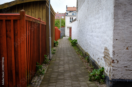 an empty deserted street with paving, masonry walls and planks on its sides