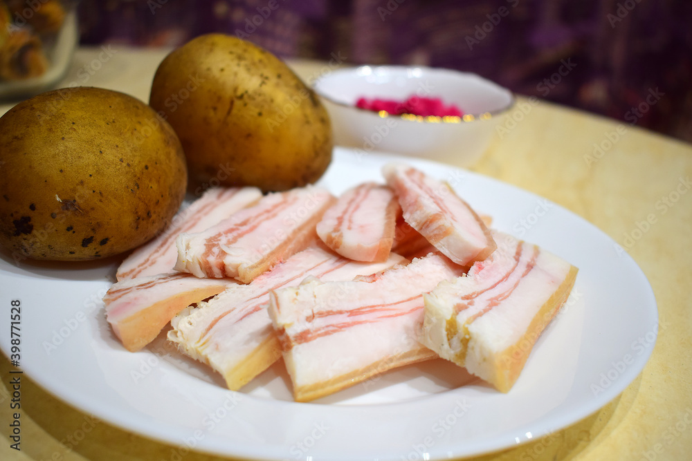 Pork fat with boiled potatoes in a uniform.