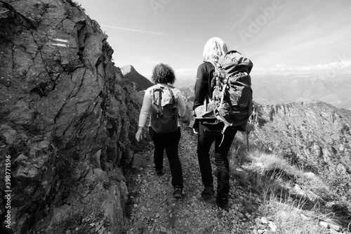 a couple of people walking on a path in the mountains