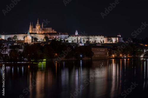 old illuminated prague castle and charles bridge and st. vita church lights from street lights are reflected on the surface of the vltava river in the center of prague at night in the czech republic © svetjekolem