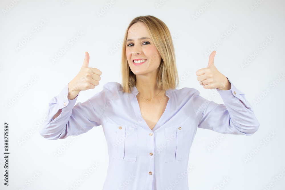 Portrait of happy young woman who is showing thumbs up over white background. Portrait of happy young woman who is showing thumbs up over white background.