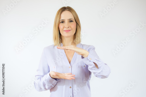 Young woman wearing casual shirt showing product with hands over white background.