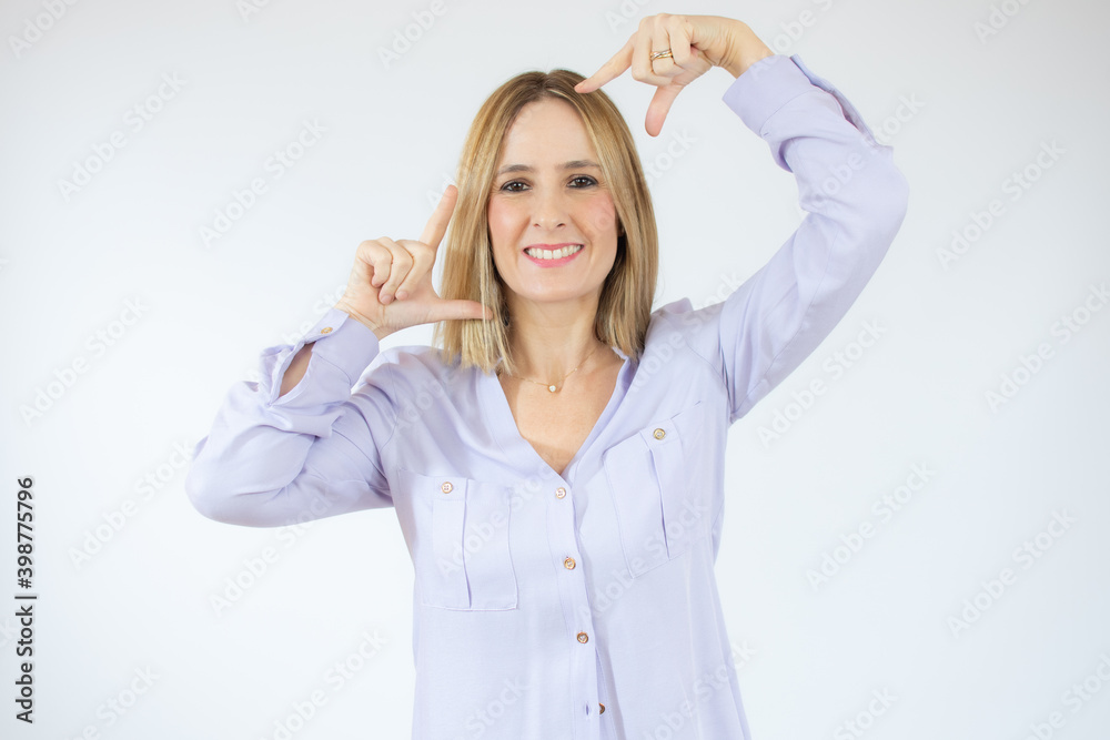Obraz premium Young beautiful woman standing over white isolated background smiling making frame with hands and fingers with happy face. Creativity and photography concept.