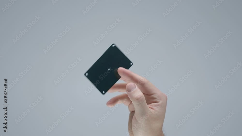 Male hand showing black plastic bank or gift card with tracking points on gray studio background Male hand showing black plastic bank or gift card with tracking points on gray studio background