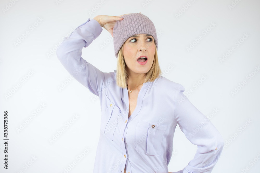 Portrait of a happy young woman wearing winter hat surprised isolated over white background