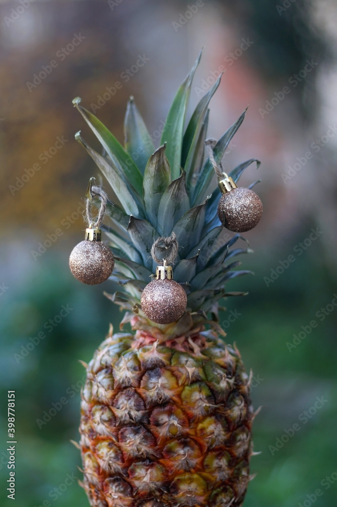 Fototapeta premium Pineapple decorated with gold Christmas baubles. Selective focus.