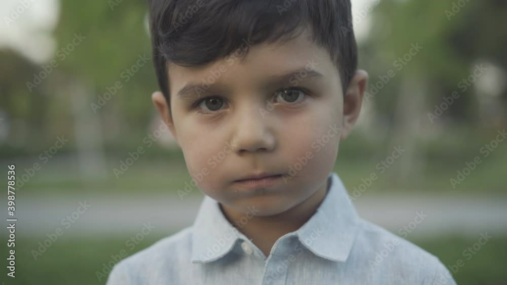 Close-up portrait of cute happy little boy chewing sweet delicious chocolate. Brunette Middle Eastern child with hazel eyes eating tasty food outdoors in summer park. Childhood concept. Close-up portrait of cute happy little boy chewing sweet delicious chocolate. Brunette Middle Eastern child with hazel eyes eating tasty food outdoors in summer park. Childhood concept.