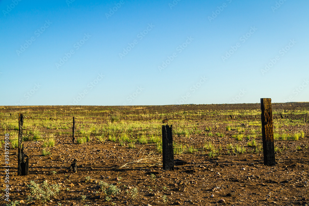 Old wood fence with fire damage on a flat prairie under a blue sky. Old wood fence with fire damage on a flat prairie under a blue sky.