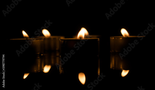 Candlelight. Many candle flames glowing on dark. Candles reflected in the water