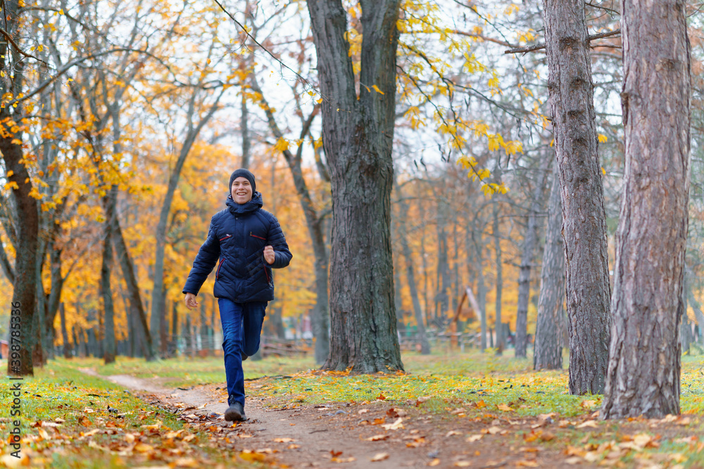 a boy running through the park and enjoys autumn, beautiful nature with yellow leaves