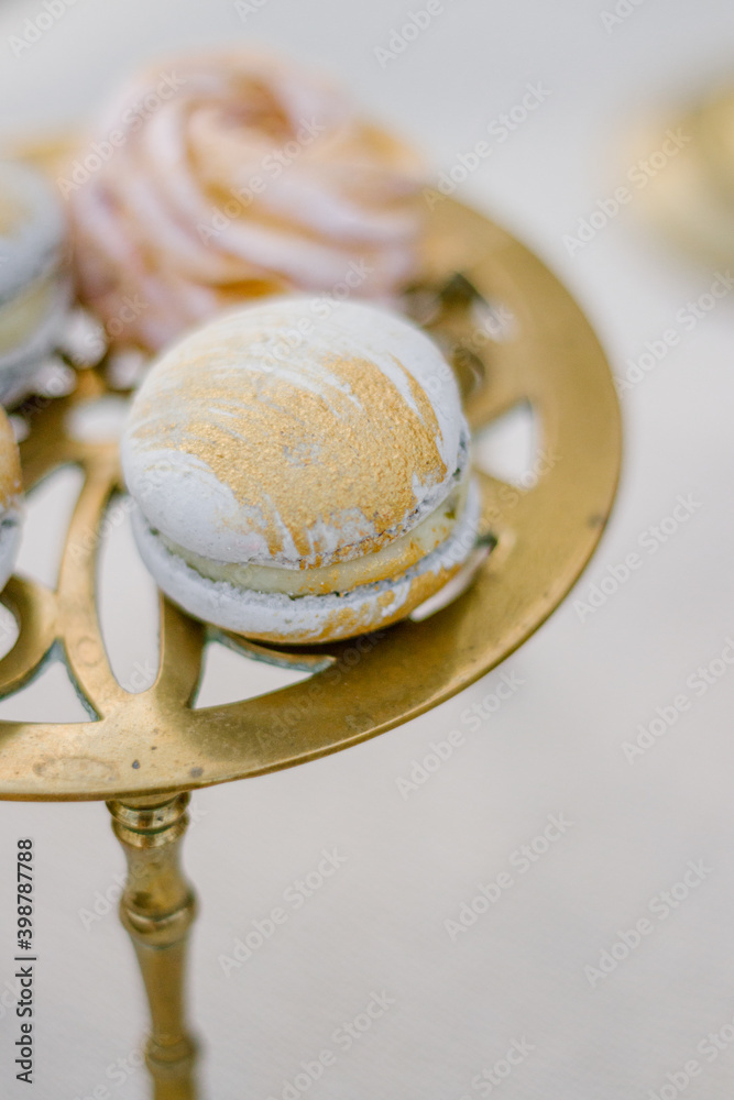 Fototapeta premium Modern trendy macaroon dessert on a gold stand close up
